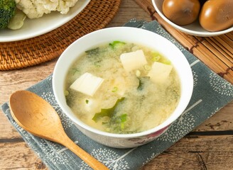 japanese style Miso soup in a white bowl with wooden spoon isolated on mat top view