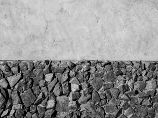 Strong wall decoration with many stones on concrete wall. Cement wall texture decorated with crack rocks, black and white style.