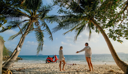 Scooter road trip. Lovely couple on red motorbike in white clothes on sand beach. Just married people kiss hugs walking near the tropical palm trees, sea. Wedding honeymoon by ocean. Motorcycle rent.