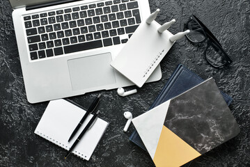 Wi-Fi router, laptop and stationery on dark background
