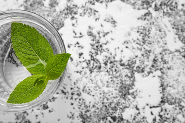 Glass of water with mint leaves on grunge background