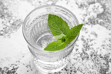 Glass of water with mint leaves on grunge background