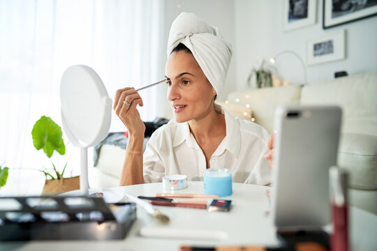 Focused woman doing makeup at home