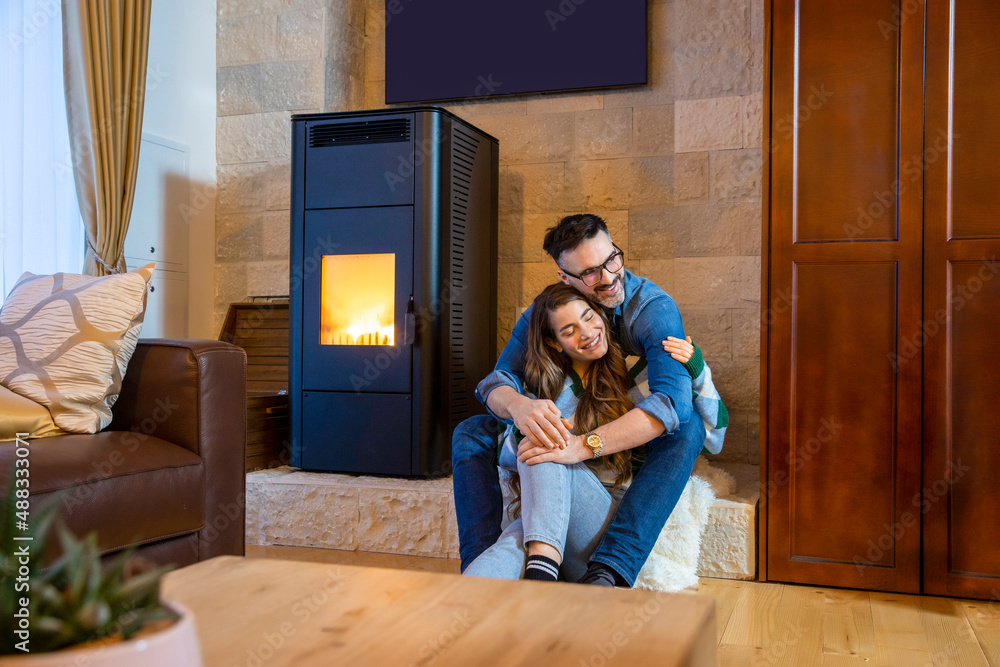 Wall mural Romantic couple enjoying together in mountain house by the fire on a cold winter day