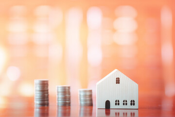 Stacks of coins on desk with mockup wooden houses; investments; business growth; saving money; transactions; taxes; building a house; borrowing money; bank deposits; financial management; target..
