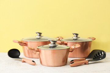 Different kitchen utensils on table near color wall
