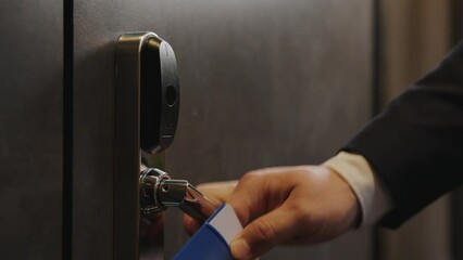 A man's hand holds up an electronic key and opens the closed door.