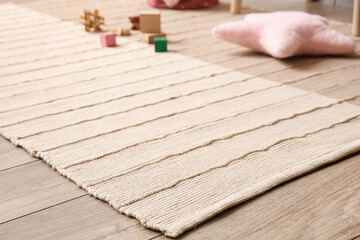 Stylish carpet on wooden floor in child room