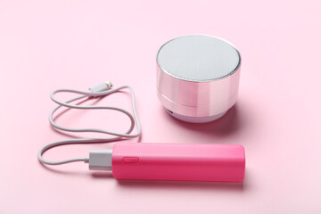 Power bank with USB cable and speaker on pink background