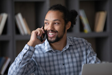 Smiling millennial handsome African American man holding cellphone call conversation, distracted...