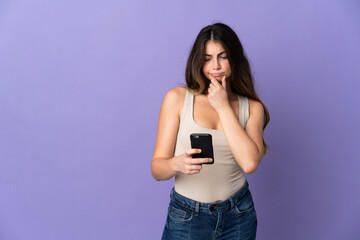 Fototapeta premium Young caucasian woman isolated on purple background thinking and sending a message