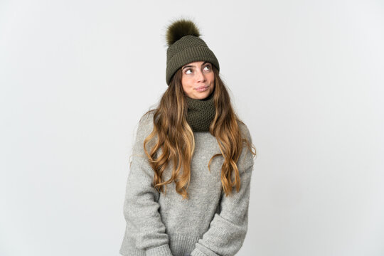 Young caucasian woman with winter hat isolated on white background and looking up