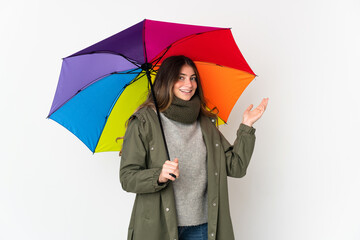 Young caucasian woman holding an umbrella isolated on white background extending hands to the side for inviting to come