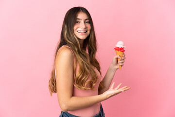 Young caucasian woman with a cornet ice cream isolated on pink background extending hands to the side for inviting to come
