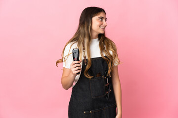 Young hairdresser woman isolated on pink background looking side