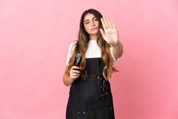 Young hairdresser woman isolated on pink background making stop gesture