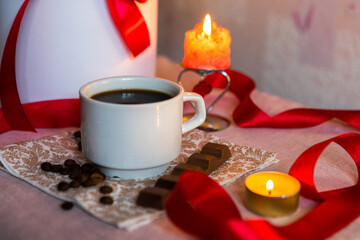 Coffee in a white cup with milk chocolate on the table against the background of red roses