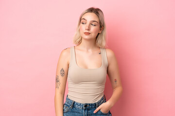 Young caucasian woman isolated on pink background having doubts while looking side