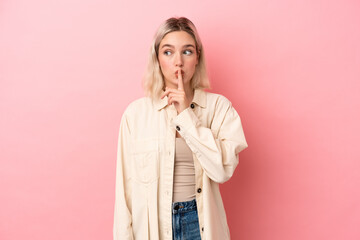 Young caucasian woman isolated on pink background showing a sign of silence gesture putting finger...