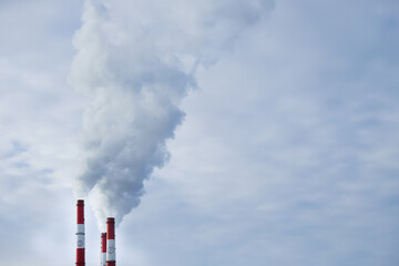 Three pipes of a thermal power plant close-up. Smoke rises from the chimneys into the sky. Copy...