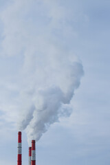 Three pipes of a thermal power plant close-up. Smoke rises from the chimneys into the sky. Place to copy. vertical.
