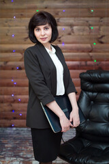 A business lady in a formal suit with a laptop in her hand on a festively decorated wooden...