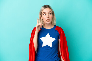 Super Hero caucasian woman isolated on blue background thinking an idea pointing the finger up