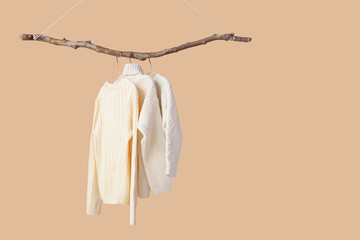 Children's sweaters hanging on color background