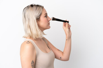 Obraz premium Young caucasian woman isolated on white background holding makeup brush