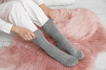 Woman wearing warm socks on fluffy rug. Concept of heating season