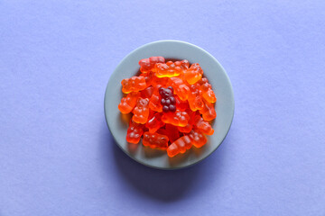 Plate with sweet jelly bears on blue background