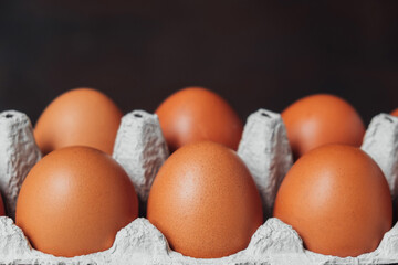 Open cardboard tray with ten brown chicken eggs on table. Ecological food product. Front view. Copy space