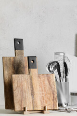 Wooden cutting boards and kitchen utensils on light background