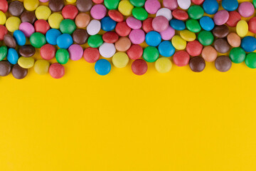 Multi-colored candies on a yellow background. Copy space.