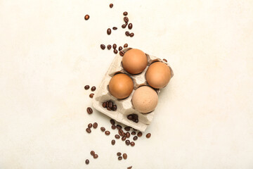 Holder with chicken eggs and coffee beans on light background
