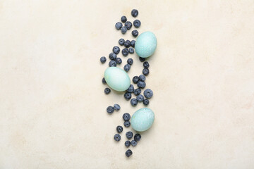 Beautiful Easter eggs and blueberry on light background