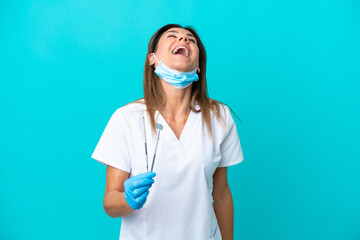 Middle age doctor woman isolated on blue background laughing