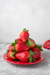 Strawberry fresh fruits in a plate, grey background. Healthy food concept
