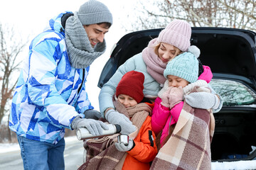 Young man with his family drinking hot tea on snowy winter day