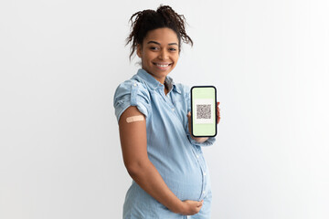 Pregnant black lady showing plaster on arm and digital certificate