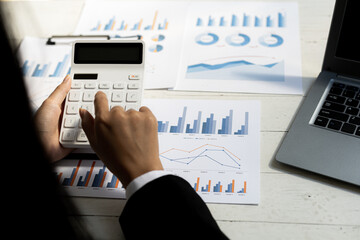 Business women using a calculator to calculate numbers on a company's financial documents, he is analyzing historical financial data to plan how to grow the company. Financial concept.