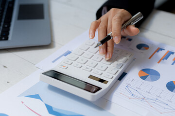 Business women using a calculator to calculate numbers on a company's financial documents, he is analyzing historical financial data to plan how to grow the company. Financial concept.