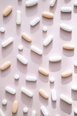 Different pills, vitamin capsules on pastel pink background. Dietary supplement supports for health.