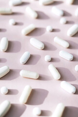 Different pills, vitamin capsules on pastel pink background. Dietary supplement supports for health.
