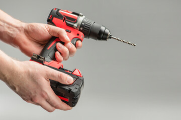 a man's hand removes the battery from a cordless tool. A man inserts a battery into a screwdriver....