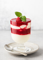 Glass of homemade fruit layered dessert with buttermilk cream, raspberry sauce layers and fresh ...