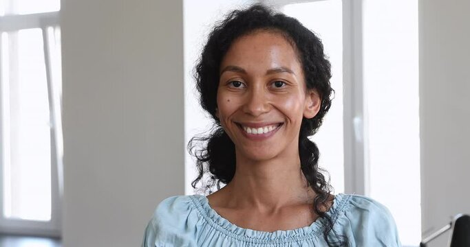 Attractive smiling African millennial female employee looking at camera posing at workplace. Head shot of professional occupation person, clerical office worker portrait, career and promotion concept