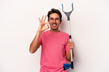 Young caucasian man holding a garbage collector isolated on white background cheerful and confident showing ok gesture.