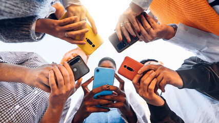 Teens in circle holding smart mobile phones - Multicultural young people using cellphones outside - Teenagers addicted to new technology concept - obrazy, fototapety, plakaty