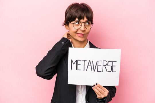 Young hispanic business woman holding a metaverse placard isolated on pink background touching back of head, thinking and making a choice.
